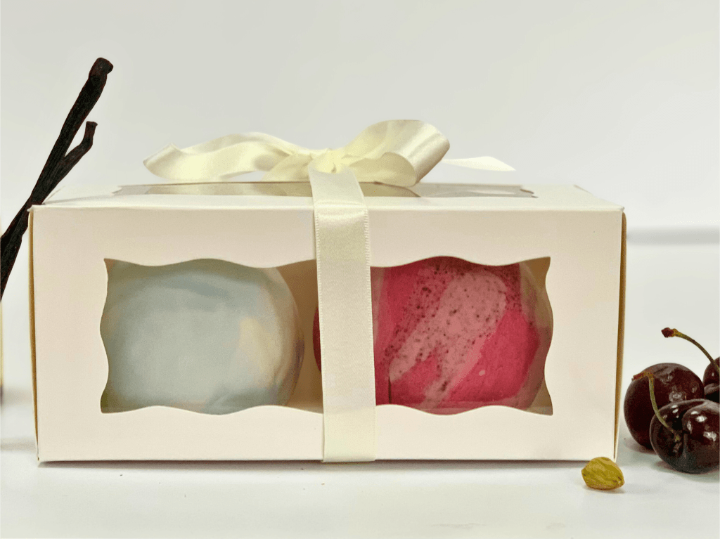 A box of two chocolate fudge cake balls in vanilla and raspberry & blackcurrant made by Cocoa & Whey Cakes